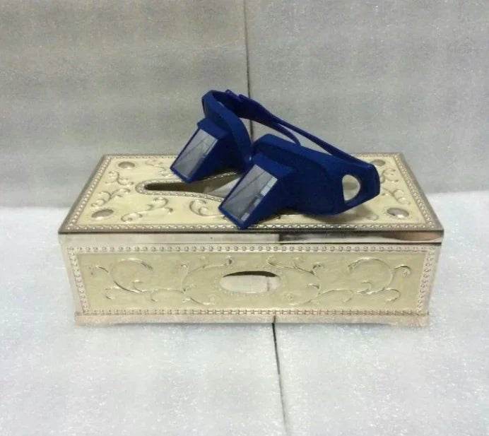 Blue prism glasses on ornate beige tissue box with embossed floral pattern
