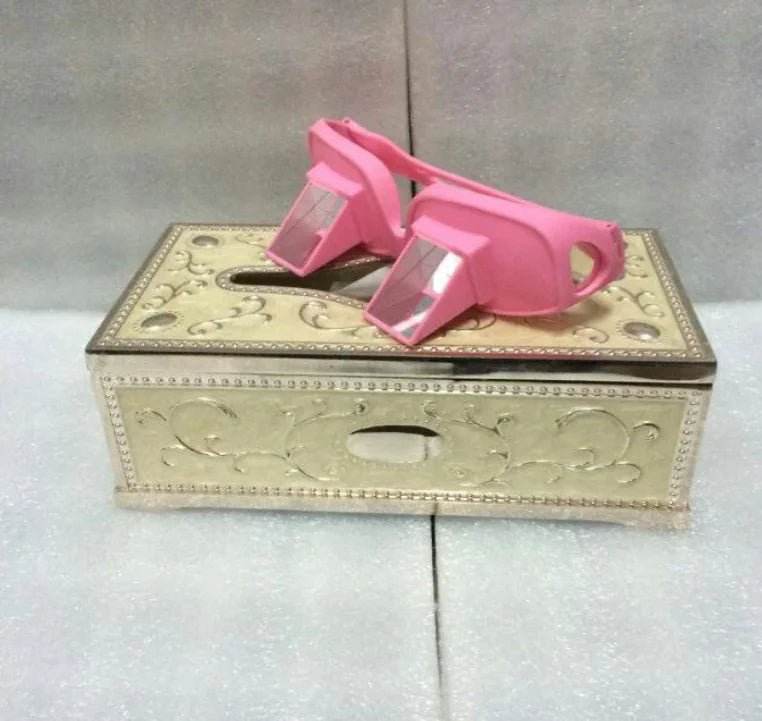 Pink prism glasses on ornate gold tissue box cover, decorative eyewear accessory