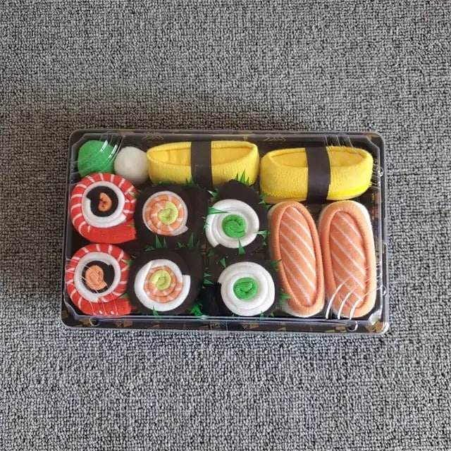 Sushi-shaped socks gift set in a plastic tray on gray fabric background